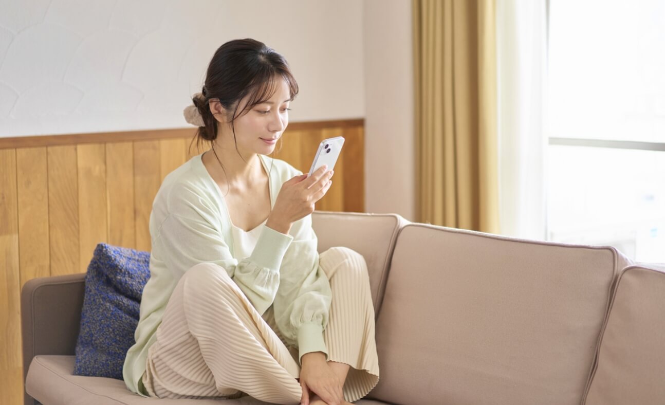 ソファに座って携帯を見ている女性